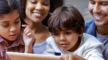 Family watching boy play on tablet